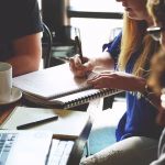 Equipo de startup trabajando en una mesa con ordenador y cuaderno