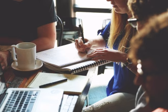 Equipo de startup trabajando en una mesa con ordenador y cuaderno