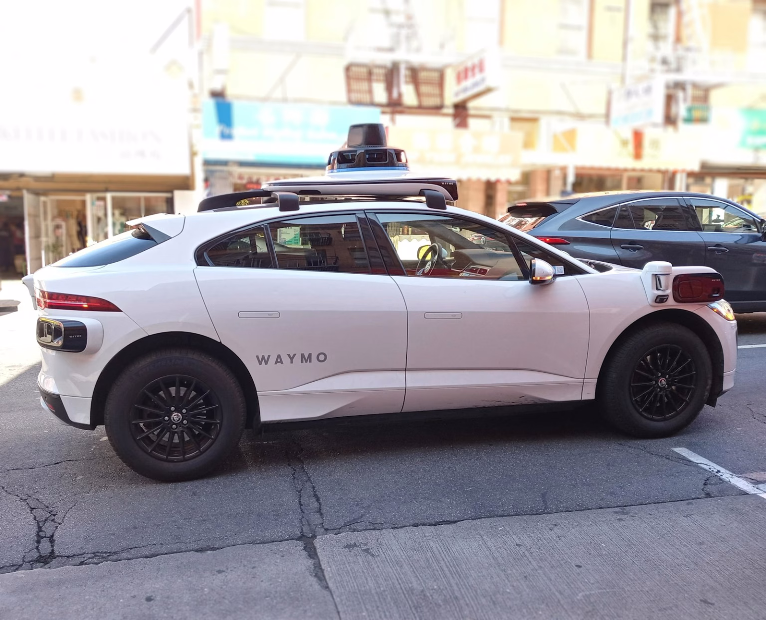 Vehículo autónomo Waymo circulando por una calle urbana, asociado a robotaxis y regulación municipal.