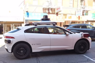 Vehículo autónomo Waymo circulando por una calle urbana, asociado a robotaxis y regulación municipal.