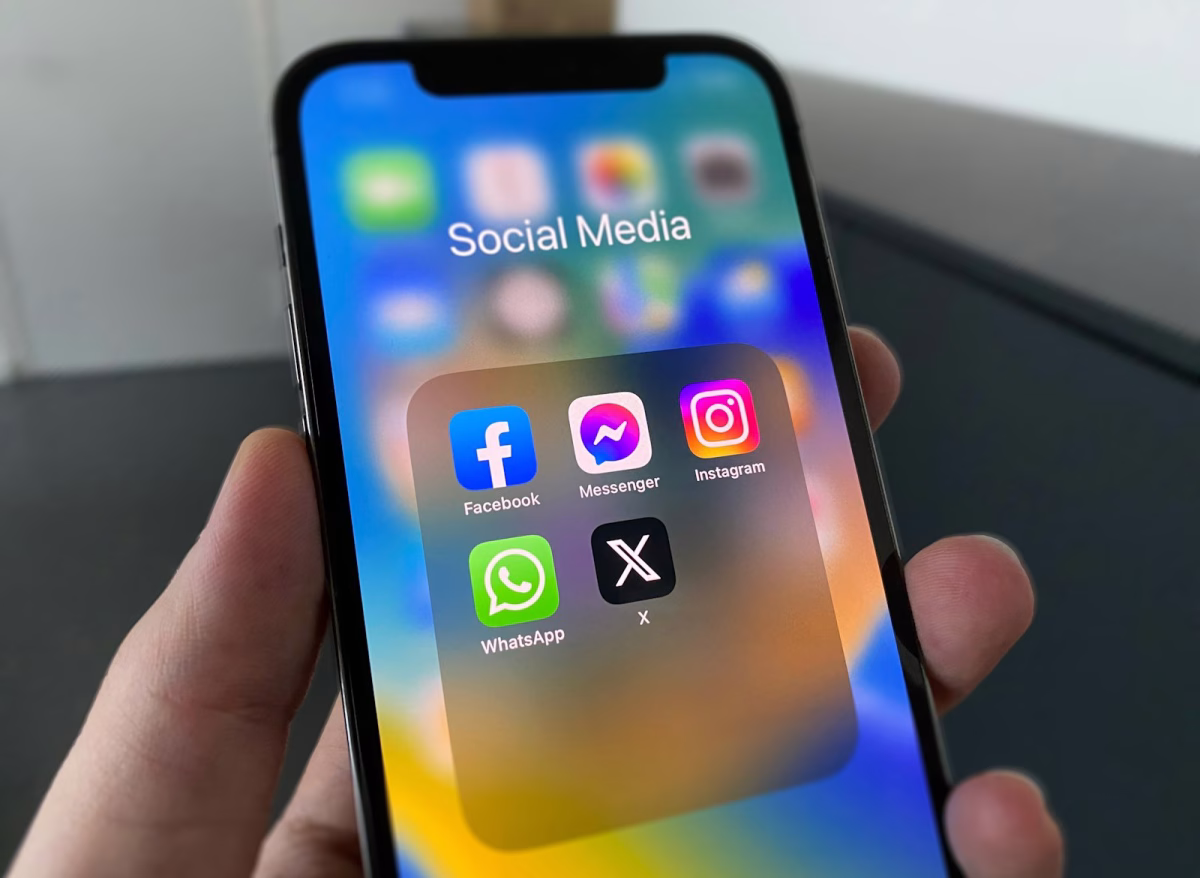 Persona usando un teléfono móvil con aplicaciones sociales en pantalla.