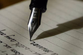 Persona escribiendo en un ordenador portatil con documentos sobre la mesa