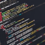 Persona programando en un portátil con varias líneas de código en pantalla.