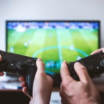 Persona usando un mando frente a una pantalla, imagen asociada a videojuegos y entretenimiento digital.