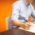 Persona trabajando en un cuaderno y un portatil durante una sesion de emprendimiento