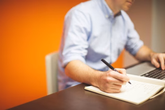 Persona trabajando en un cuaderno y un portatil durante una sesion de emprendimiento