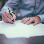 Persona revisando documentación financiera y legal en una mesa de trabajo.