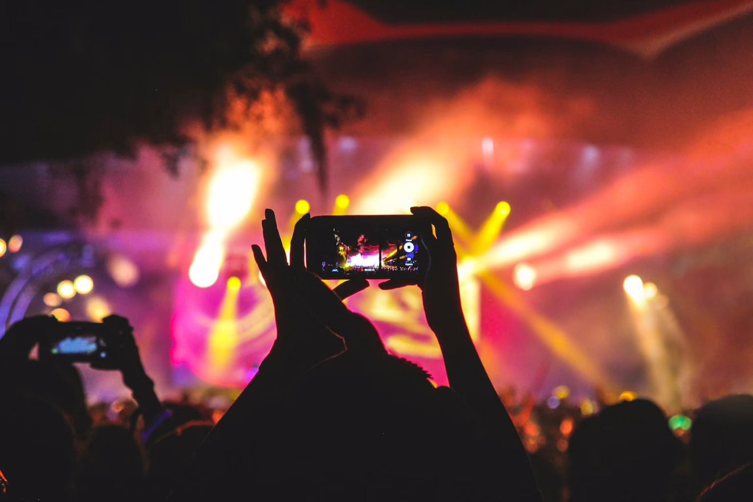 Personas entrando a un evento cultural con luces de escenario, imagen asociada a ticketing y entretenimiento en vivo.