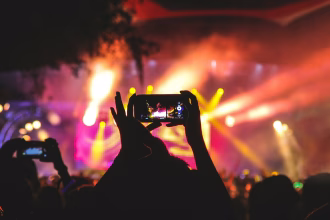 Personas entrando a un evento cultural con luces de escenario, imagen asociada a ticketing y entretenimiento en vivo.