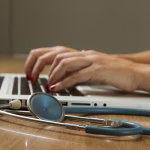 Profesional sanitario revisando un dispositivo medico en una mesa de trabajo.